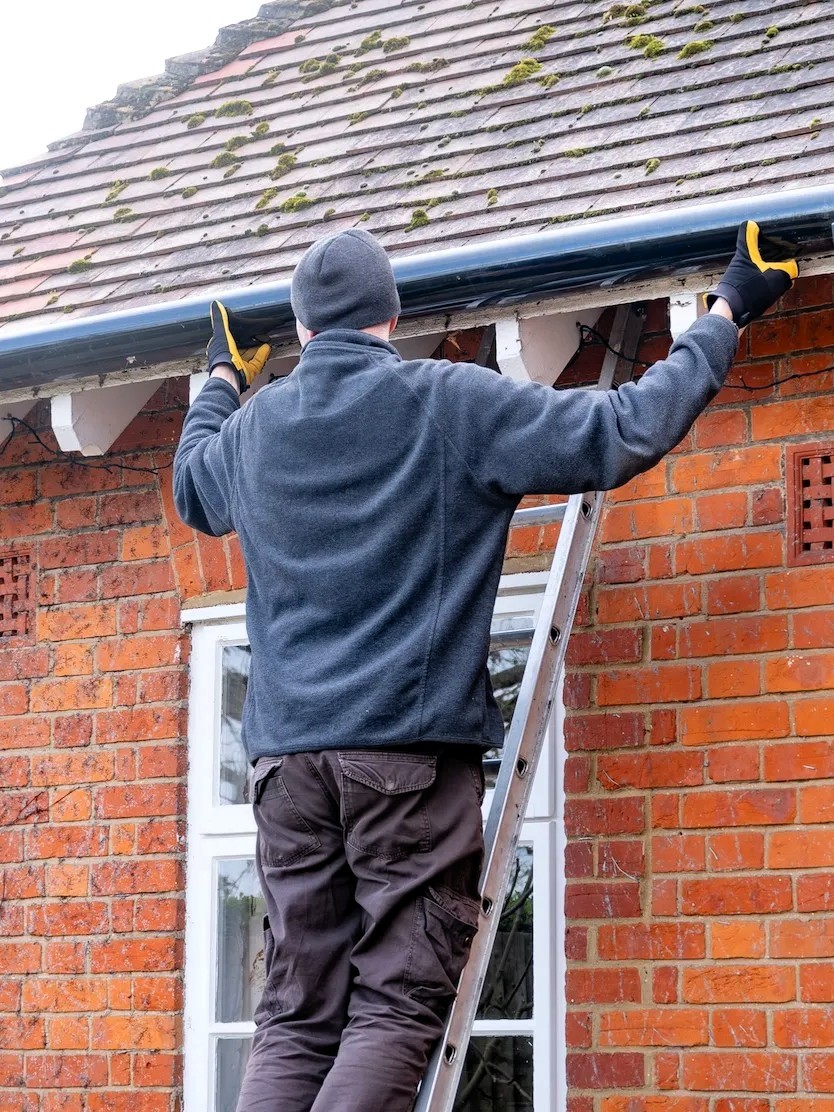 Guttering contractor adjusts guttering system after installing new guttering component in Dorset
